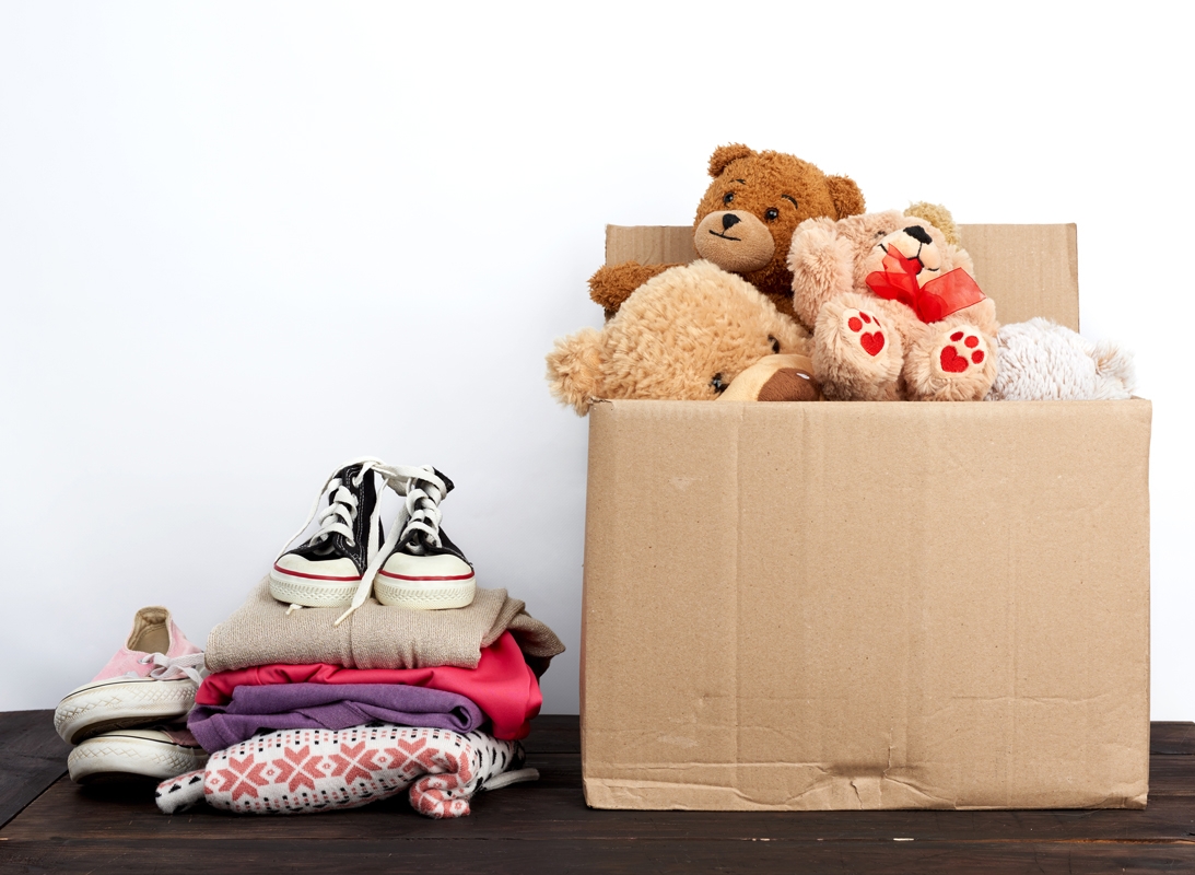 pile de vêtements à donner avec un carton d'objets