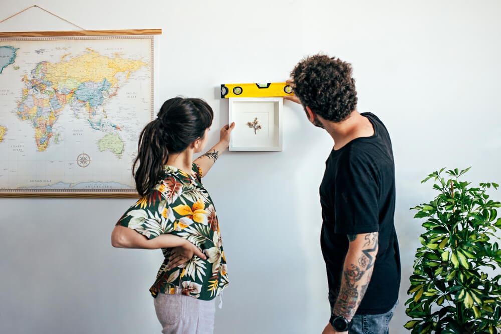 Couple qui accroche un cadre au mur