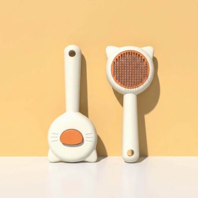 Brosse pour chat blanche vue de dos et de face, avec ses oreilles et ses picots orange
