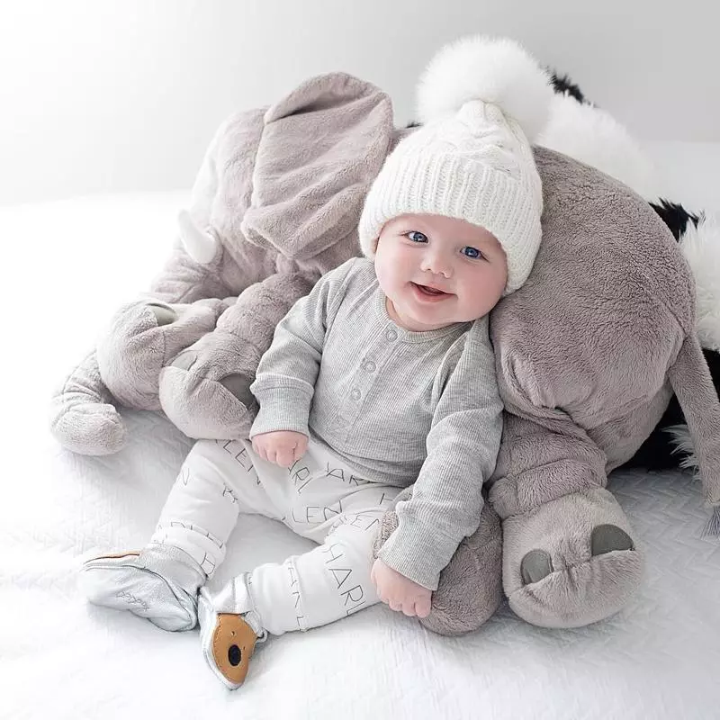 Enfant souriant assis sur l'oreiller éléphant en peluche